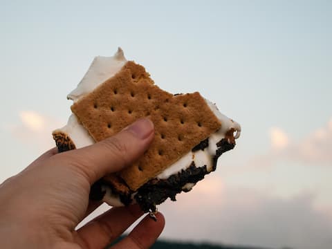Hand holding a toasted s’more with marshmallow and graham cracker during a quiet evening near Smith Mountain Lake.