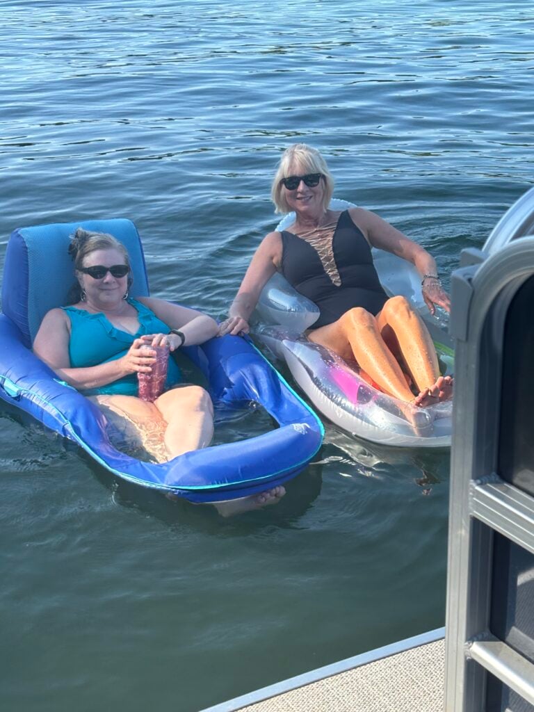 Guests relaxing on floats beside a boat during a sunny Smith Mountain Lake outing near Bedford Landings Bed & Breakfast.