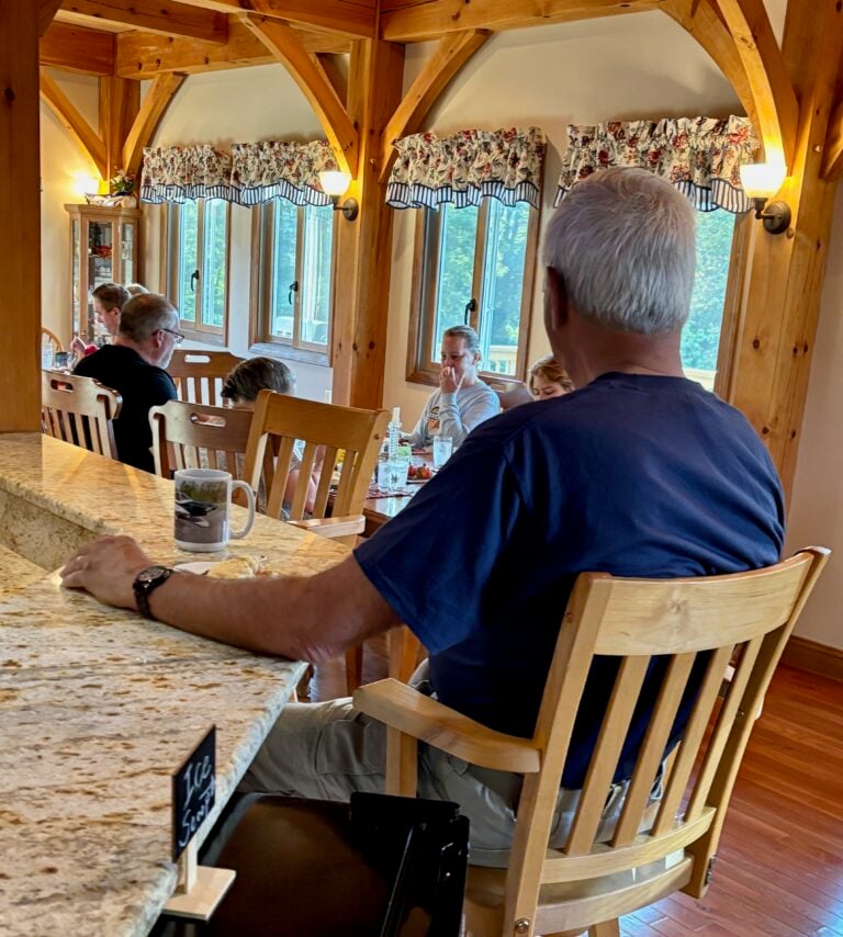 Guests enjoying a hosted breakfast in the warm wood dining room at Bedford Landings Bed & Breakfast near Smith Mountain Lake.
