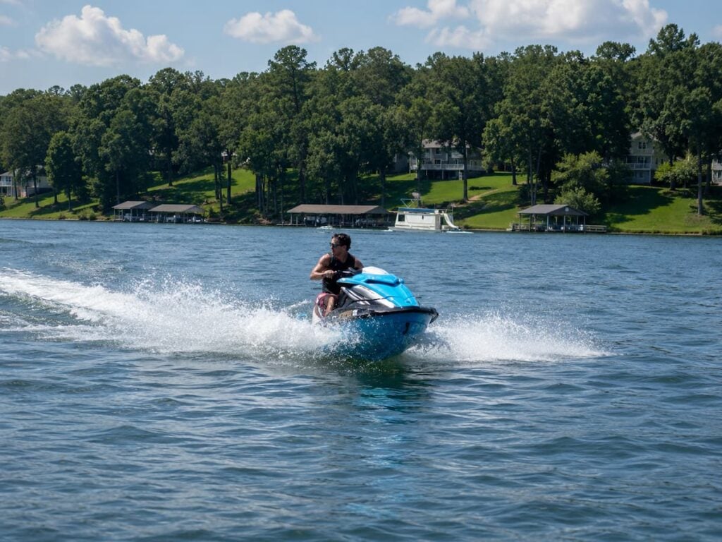 Person riding a jet ski across Smith Mountain Lake near Bedford Landings Bed & Breakfast on a sunny day.