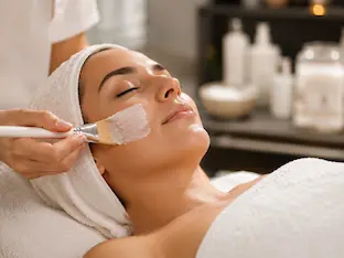 Woman receiving a relaxing spa facial treatment with skincare mask applied by an esthetician.